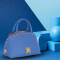 Stylish blue marigold satchel bag with studs on blue background.