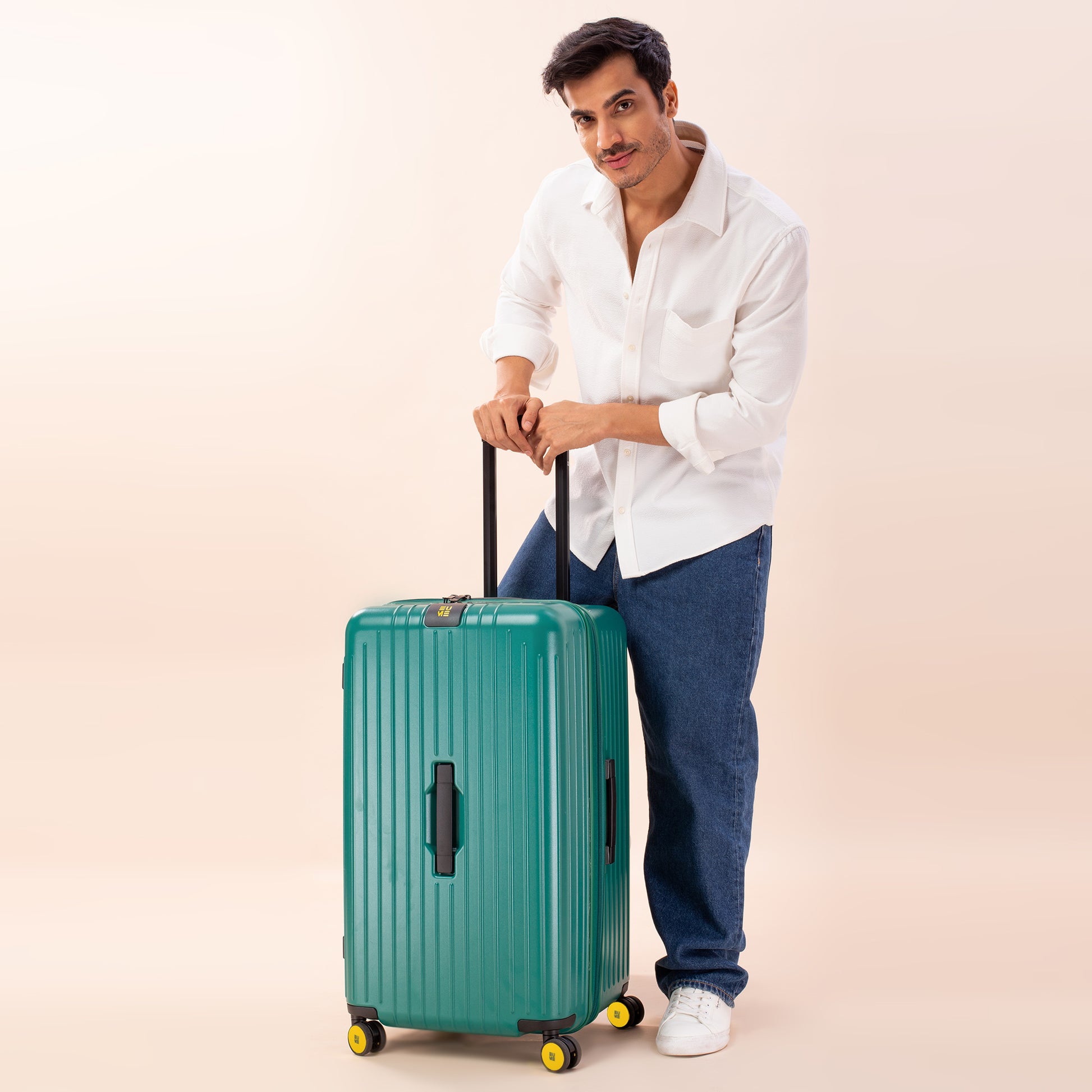 Stylish man with teal Trunk Check-In Plus suitcase on wheels.