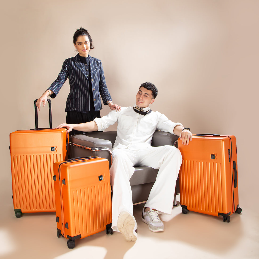 Two orange rolling suitcases with black handles and wheels.