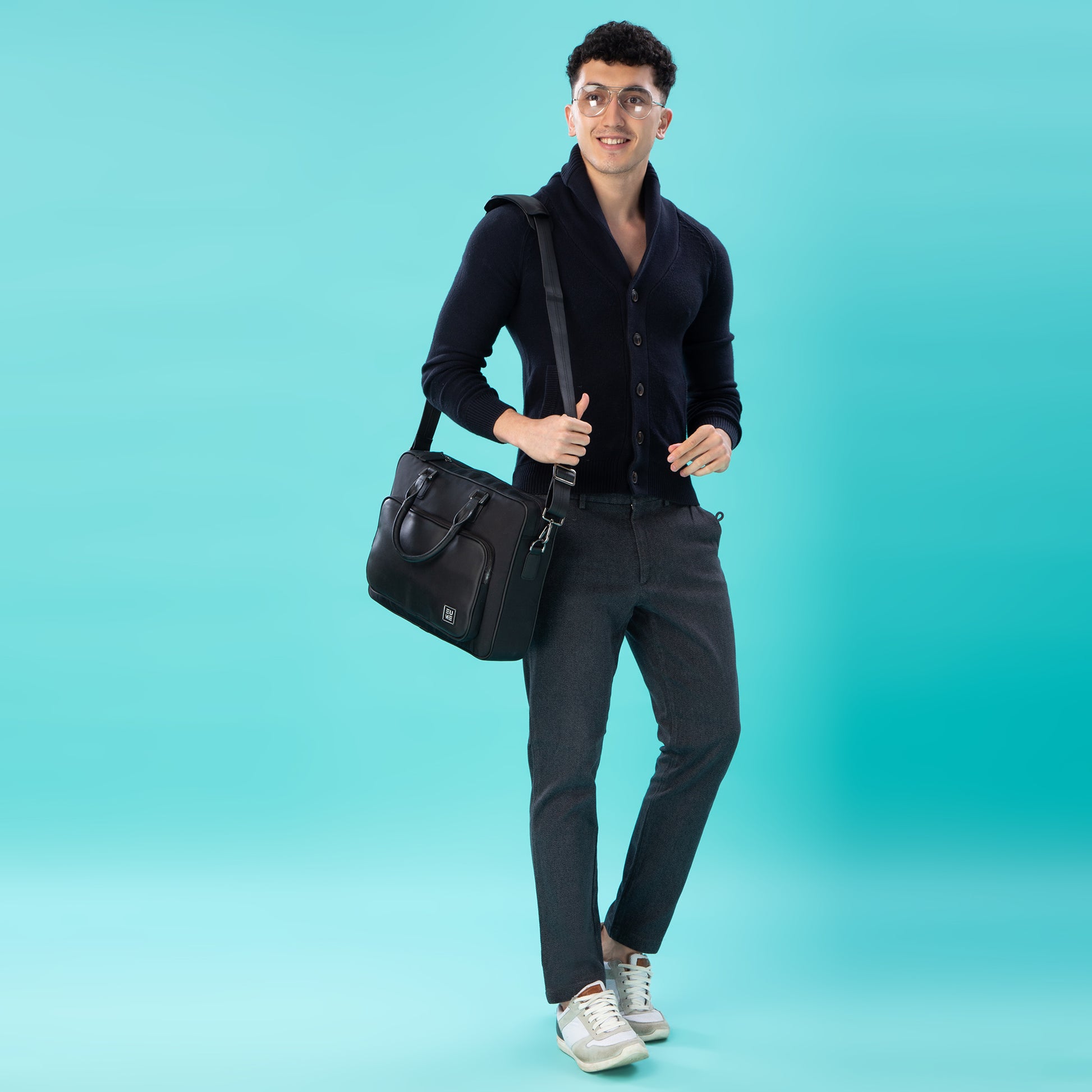 Stylish man with executive messenger bag on a turquoise background.