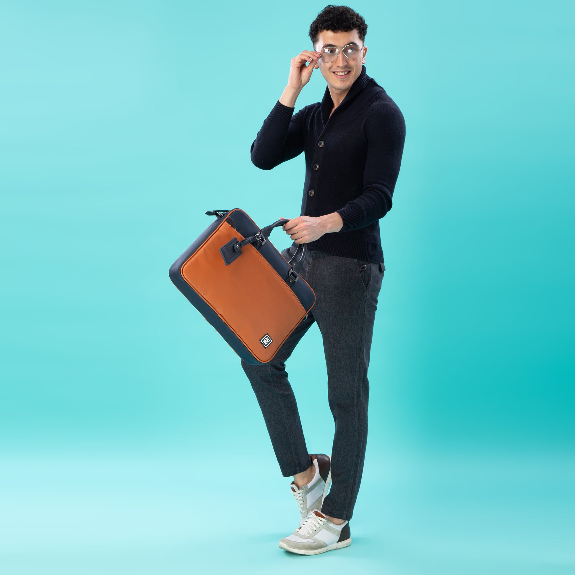 Stylish man holding Commute Messenger Bag against turquoise background.