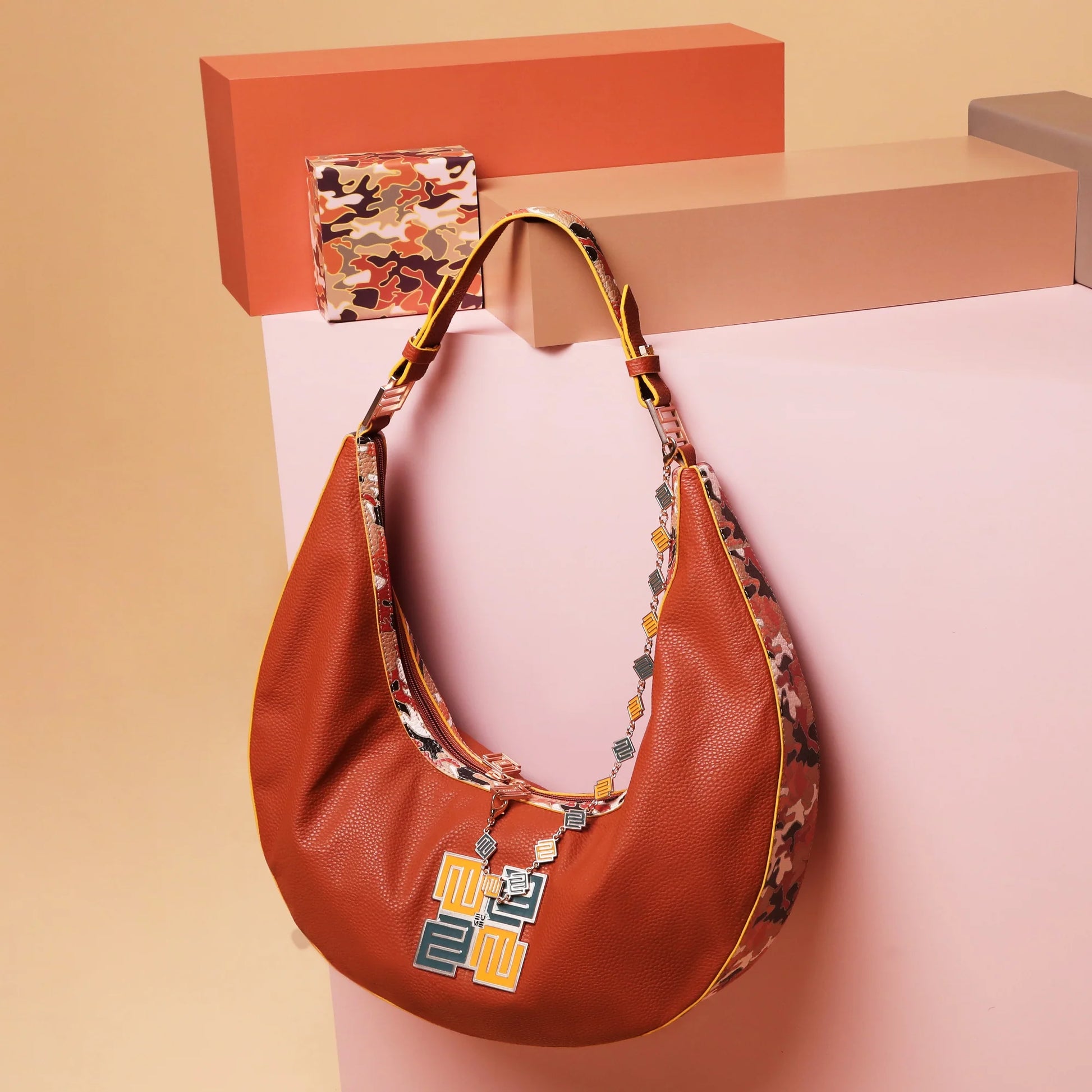 Cinnamon hobo bag with stylish floral strap and modern design.