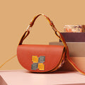 Stylish Pecan Saddle Bag with colorful strap and decorative emblem.