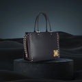 Daffodil Satchel Laptop Handbag with studded detail on a dark background.