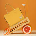 Daffodil Satchel Laptop Handbag on colorful display with accessories.