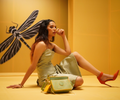 Model showcasing Damsel Saddle 2-in-1 detachable handbag against yellow backdrop.