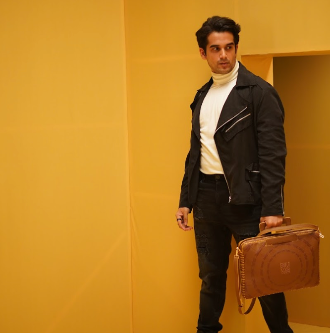 Stylish man holding Dasher Laptop Sleeve against a yellow backdrop.