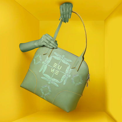 Luna Bowling Handbag in green with stylish design against yellow background.