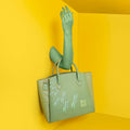 Stylish green Spreadwing Tote Handbag against vibrant yellow backdrop.