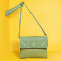 Stylish green Streamer Messenger Bag on a bright yellow background.